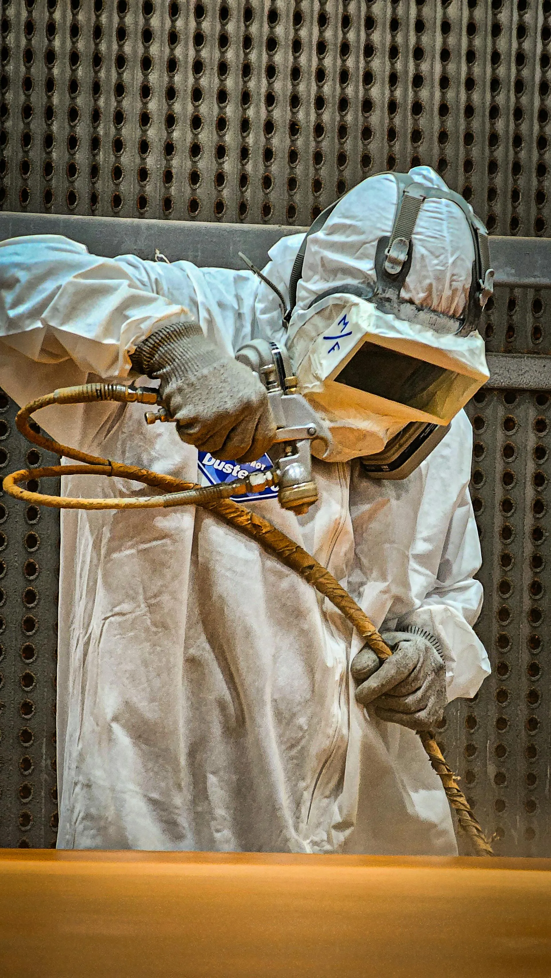 Ouvrier industriel en équipement de protection effectuant un sablage abrasif